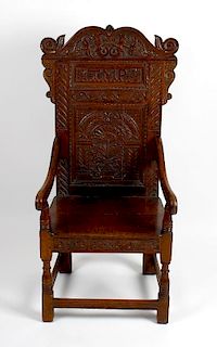 An early 20th century carved oak Wainscot-style chair. The foliate scrolling crest above carved back