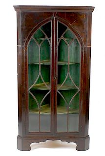An early 19th century mahogany-veneered floor-standing corner cabinet. The moulded cornice with dent