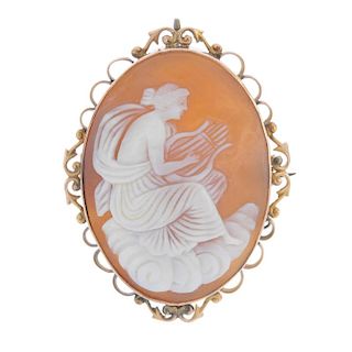 A cameo brooch. The shell carved to depict a goddess sitting on a cloud, playing a lyre, to the scro