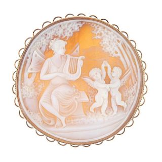 A 9ct gold cameo. Of circular outline, the cameo depicting a winged lady playing a lyre for two danc