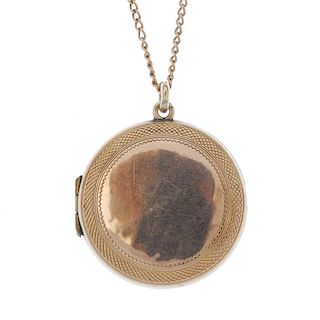 A circular-shape locket. With geometric engraved edge, suspended from a curb-link chain. Length of l