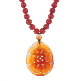 A Chinese carved agate necklace. The floral-carved agate beads suspending a carved panel depicting t