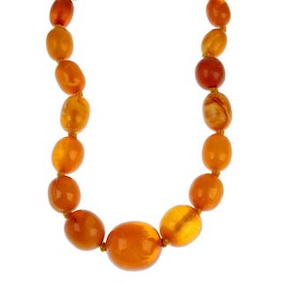 A natural amber necklace. Comprising a single row of twenty-four graduated oval-shape beads measurin