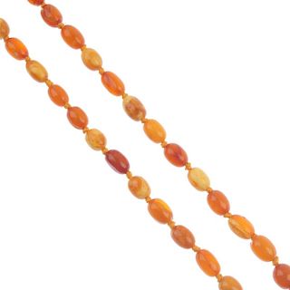 A natural amber necklace. Comprising thirty-eight graduated oval-shape beads (including one plastic
