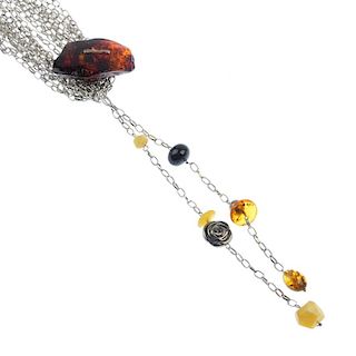 Two stainless steel and amber necklaces and a rough piece of amber. The necklaces both designed as m