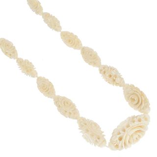 An early 20th century ivory necklace. Designed as a series of graduated carved beads, each of foliat