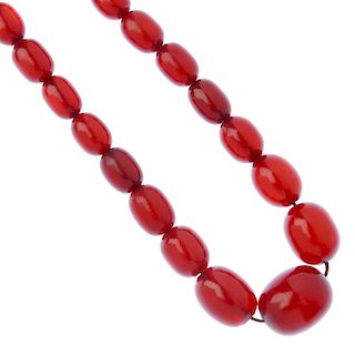A red plastic bead necklace. Comprising thirty-five graduated oval-shape plastic beads, measuring 2.