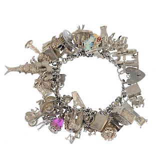 A silver charm bracelet. The belcher-link chain suspending forty-four charms including a holy bible