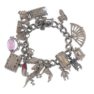 A mid 20th century charm bracelet. The curb-link chain, suspending eighteen charms, to include a cro