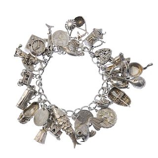 A charm bracelet. The curb-link chain suspending twenty-seven charms to the heart padlock clasp. Mos