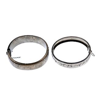 A selection of four silver bangles. To include a mother-of-pearl hinged bangle, a 1960s scroll engra