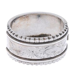 Two late 19th century silver hinged bangles. The first engraved to depict three birds on branches wi