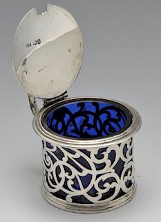 An early Victorian silver mustard pot with blue glass liner, the circular form with foliate scroll o