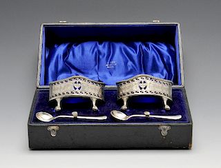 A cased pair of Edwardian silver open salts, the oval pierced bodies with beaded border, blue glass