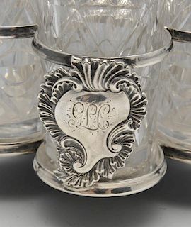 A late Victorian silver cruet stand for five bottles, having central baluster stem leading to a scro