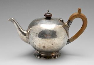 A late Victorian silver teapot of globular form having scroll capped wooden handle raised upon foote