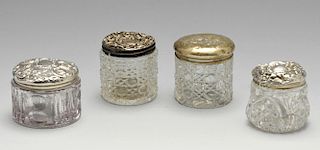 Four assorted Edwardian and later silver topped glass vanity jars of circular form, one lid decorate
