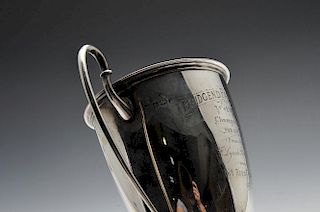 An Edwardian silver trophy cup of circular tapering form to a footed base, having a moulded rim, twi