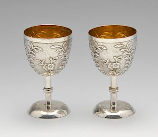 A pair of small Chinese export goblets, each decorated in relief with flowers and leafy stems agains