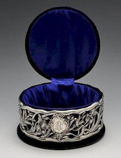 An Edwardian Art Nouveau silver mounted jewellery box, the circular velvet covered box with domed li