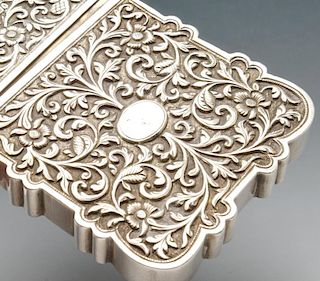 A continental card case, the deep oblong form with scalloped edge and chased with floral scroll deco