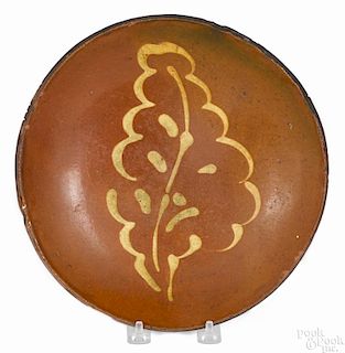 Pennsylvania redware plate, 19th c., with yellow slip leaf decoration, 10'' dia.