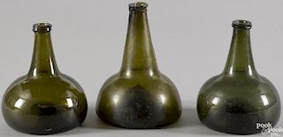 Three blown olive glass squat bottles, late 18th c., 6 1/2'' h., 7 3/4'' h., and 6 3/4'' h.