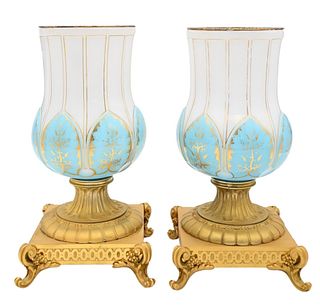 Pair of French Opaline and Bronze Urns, having blue and white opaline glass on gilt bronze bases, height 12 1/4 inches, repaired tops.