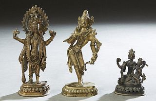 Three Oriental Bronze Shiva Figures, early 20th c., consisting of a dancing example; a standing example; and a seated example with a child, each on an