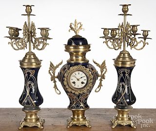 French three-piece porcelain and tin clock set with a pair of candelabra, 19 1/2'' h.