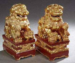 Pair of Chinese Gilt and Carved Red Lacquered Wood Foo Dogs, 20th c., on integral stepped rectangular bases, H.- 15 1/2 in., W.- 6 1/4 in., D.- 9 3/8 