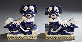 Pair of Polychromed Glazed Ceramic Foo Dogs, 20th c., in blue and white on an integral rectangular base with relief blue and green leaf decoration, H.