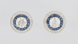 Pair of 14K White Gold Pierced Circular Earrings, with central 1.51 ct. round diamonds atop a border of trapezoidal and round blue sapphires, within a