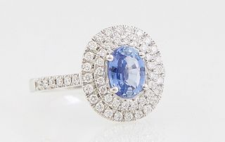 Lady's Platinum Dinner Ring, with an oval 1.32 carat blue sapphire atop a double graduated concentric border of small round diamonds, the shoulders of