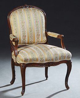 French Louis XV Style Carved Walnut Fauteuil, late 19th c., the arched floral carved crest rail over an upholstered back and arms, and a bowed cushion