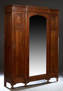 French Louis XVI Style Carved Walnut Armoire, c. 1900, the breakfront crown over a central wide beveled mirror door flanked by reeded rounded pilaster