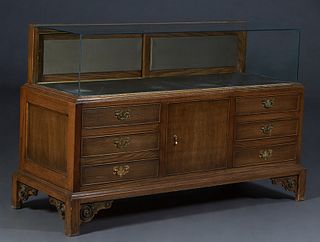 Upright Carved Oak Store Display Cabinet, with a glass top, sides and back over two rear doors, the front with three faux drawers, on block feet with 
