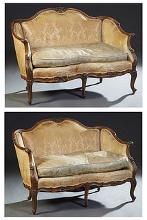 Pair of Louis XV Style Carved Walnut Settees, early 20th c., the serpentine floral carved crest rail over an upholstered back and arms, over a serpent