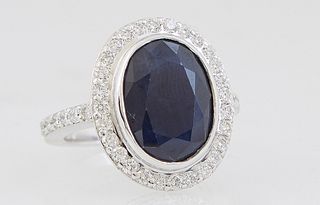 Lady's 14K White Gold Dinner Ring, with an oval 7.34 ct. blue sapphire, atop a border of small round diamonds, the shoulders of the band also mounted 