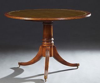 Georgian Style Carved Mahogany Center Table, 20th c., the circular reeded edge top with an inset gilt tooled green leather, on a turned tapered suppor