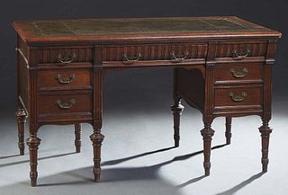 Diminutive English Carved Mahogany Desk, c. 1890, the rounded corner stepped top with an inset gilt tooled leather writing surface, over a center frie