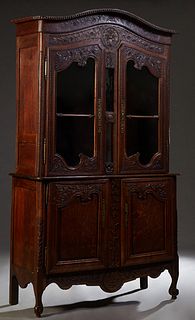 French Louis XV Style Carved Oak Buffet a Deux Corps, 19th c., the arched bowfront rounded corner crown over a floral and leaf carved arched frieze, a
