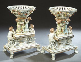Pair of Dresden Style Porcelain Figural Center Bowls, 20th c., the tapered reticulated floral encrusted bowl on a round support flanked by four childr