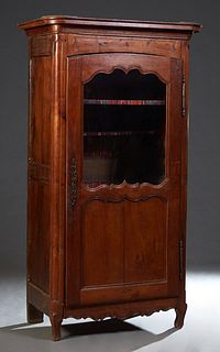 French Louis XV Style Carved Walnut Bonnetiere, 19th c., the stepped rounded corner crown over a two panel door with a glazed upper panel over a wood 