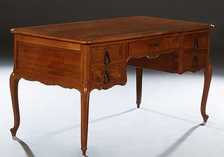 French Louis XV Style Carved Cherry Desk, early 20th c., the sloping edge rounded corner top over a center frieze drawer, flanked by two drawers with 
