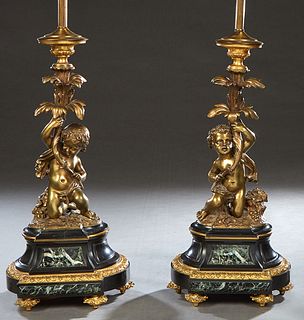Pair of Gilt Bronze Figural Candlesticks, early 20th c., each with a putto upholding a tree form leafed candlestick, on a bronze mounted sloping black