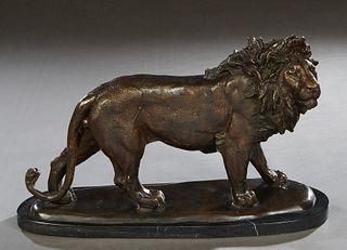 After Antoine Barye (1796-1875), "Walking Male Lion," 20th/21st c., patinated bronze, on an oval black marble base, BH.- 12 in., W.- 19 1/4 in., D.- 6