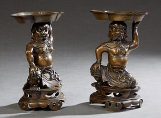 Pair of Oriental Patinated Bronze Figures, early 20th c., of a kneeling man with a lobed basket on his head, on an integral pierced socle support, on 