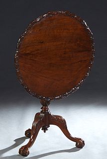 English Victorian Style Carved Mahogany Tilt Top Tea Table, 20th c., the circular top with s relief floral carved border, on a turned tapered support 