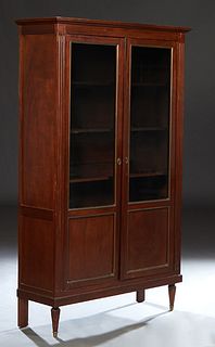 French Louis XVI Style Carved Walnut Booklcase, 20th c., the stepped rounded crown over double doors with glazed upper panels over wood lower panels, 